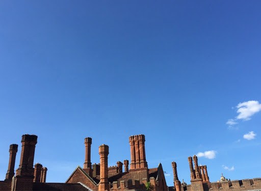 A row of ornate brick chimney stacks against a blue London sky