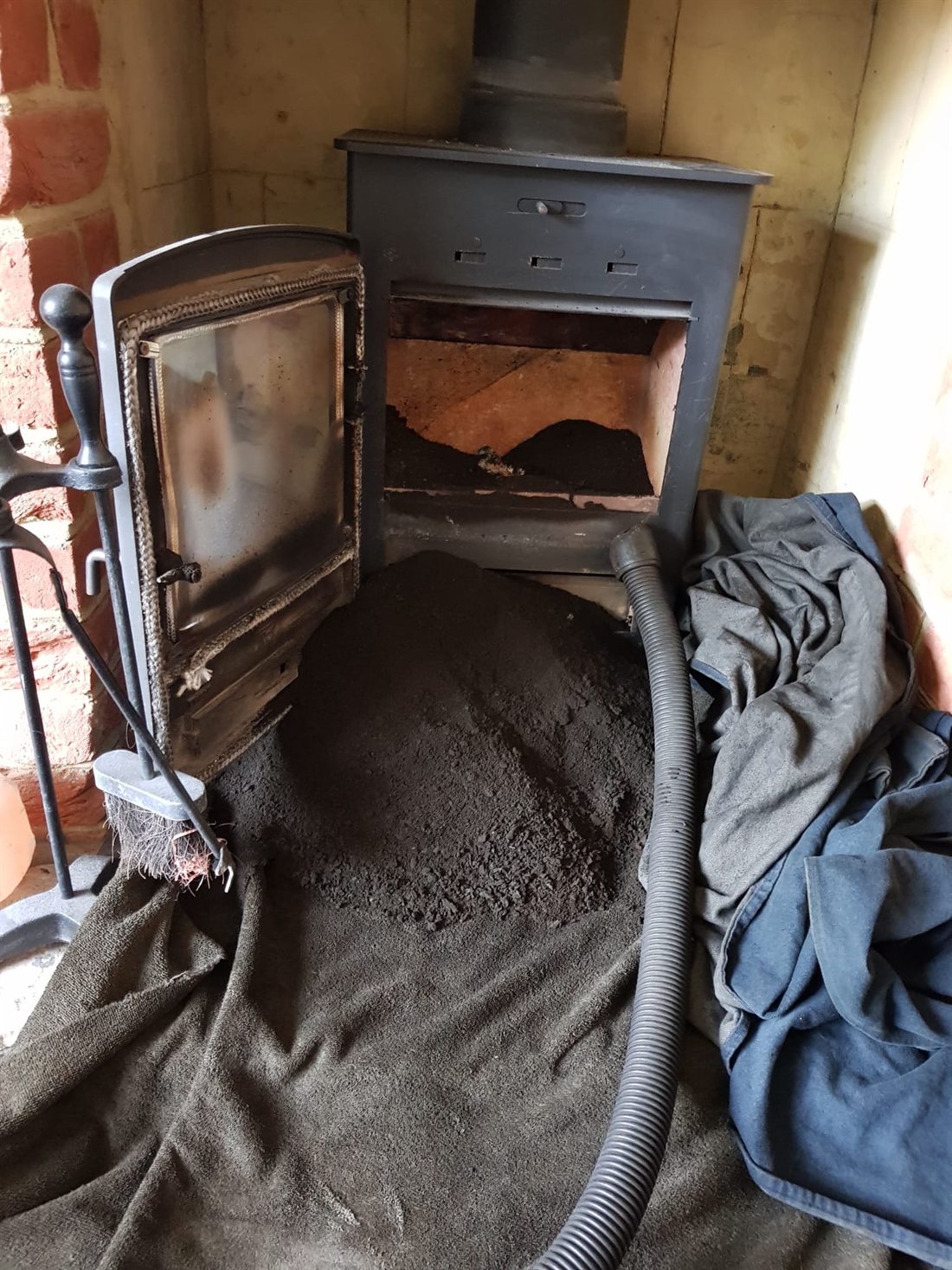 Soot swept out of a wood burning stove onto dust sheets, ready to be bagged and removed